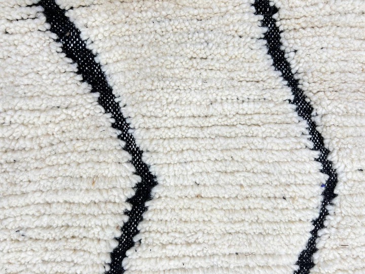 Handwoven Moroccan wool rug with black geometric diamond line pattern