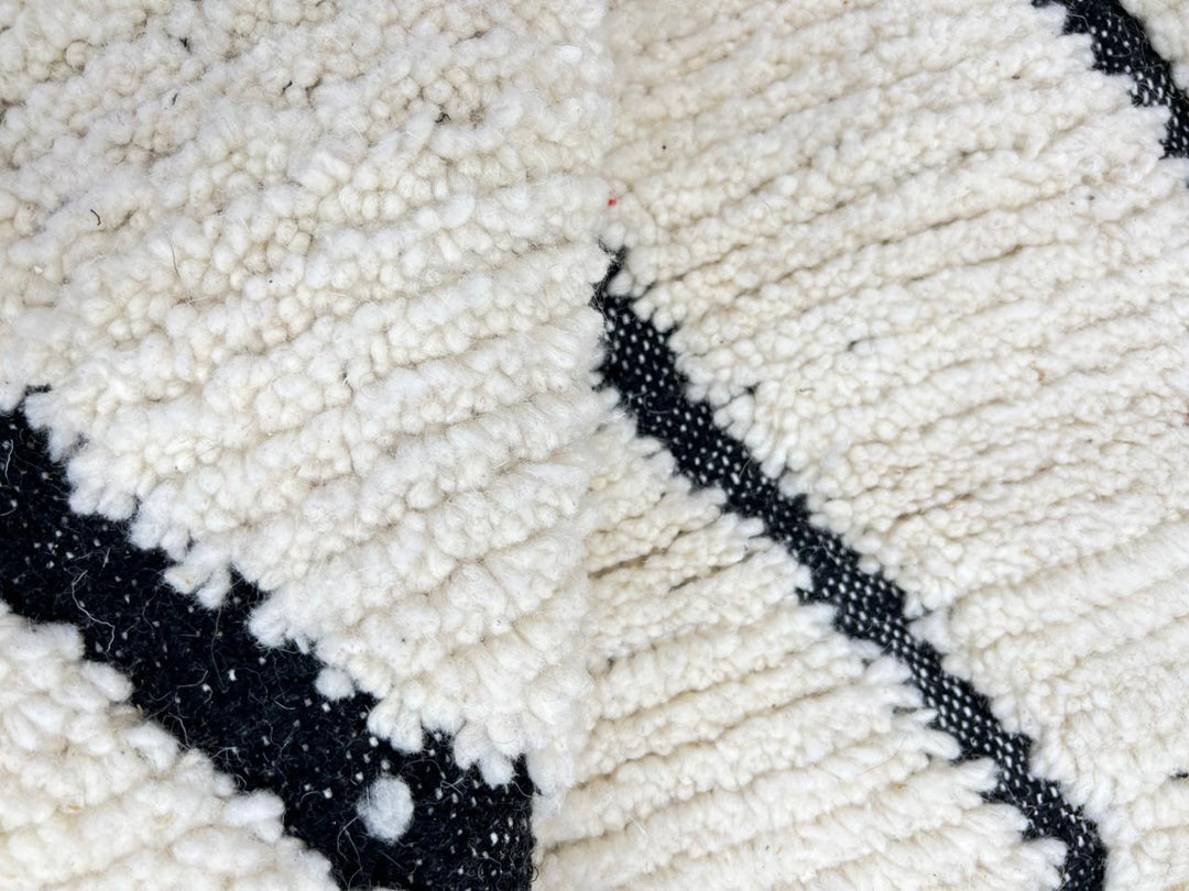 Handwoven Moroccan wool rug with black geometric diamond line pattern