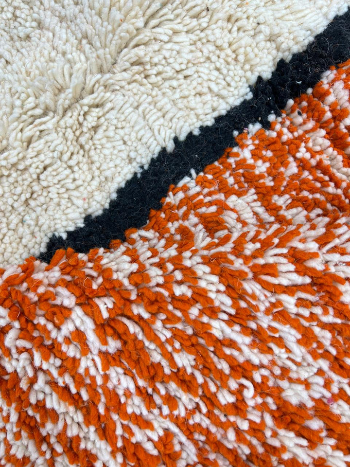 Handmade Moroccan wool rug with geometric color block design in orange, black, teal, and pink tones