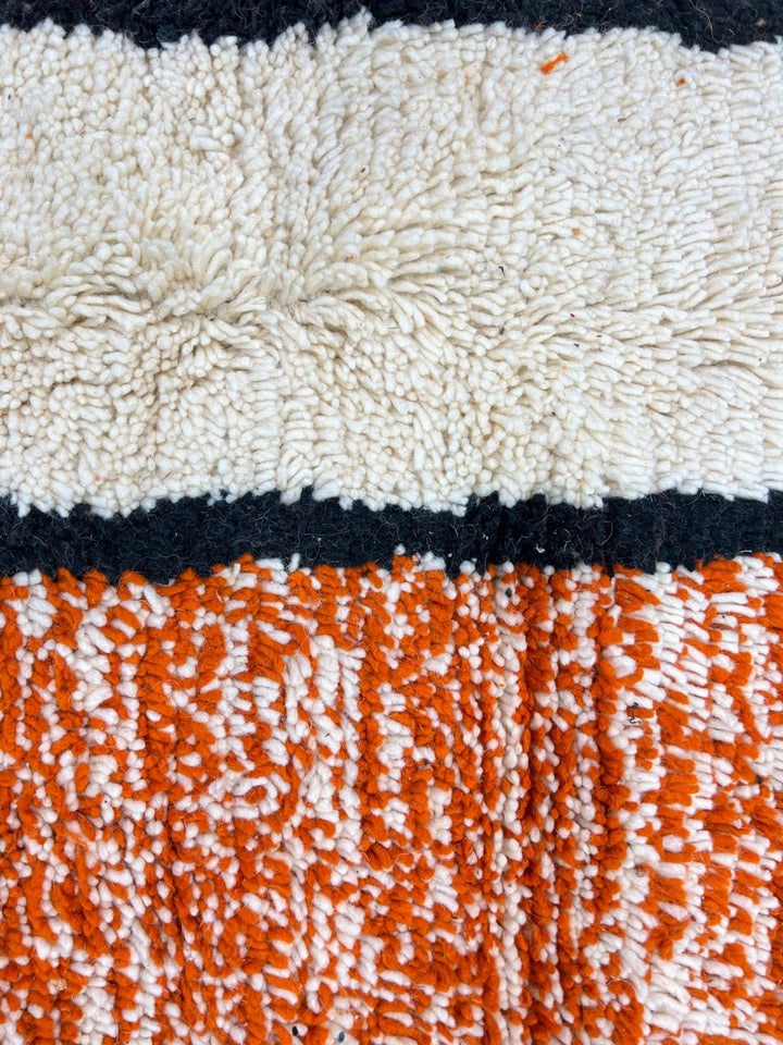 Handmade Moroccan wool rug with geometric color block design in orange, black, teal, and pink tones