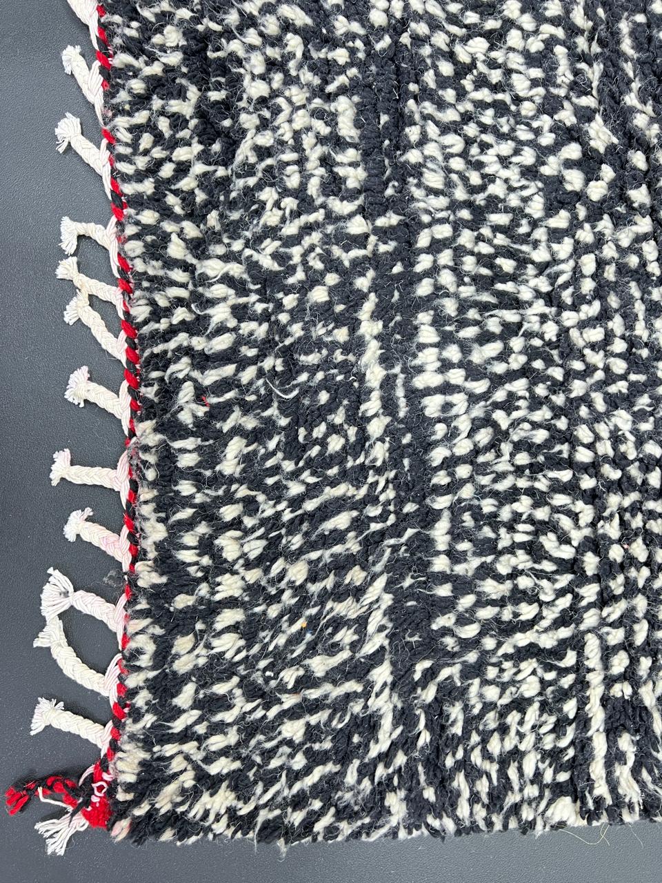 Handmade modern Moroccan runner rug with black, white, and red abstract design, crafted from natural wool by Berber artisans.