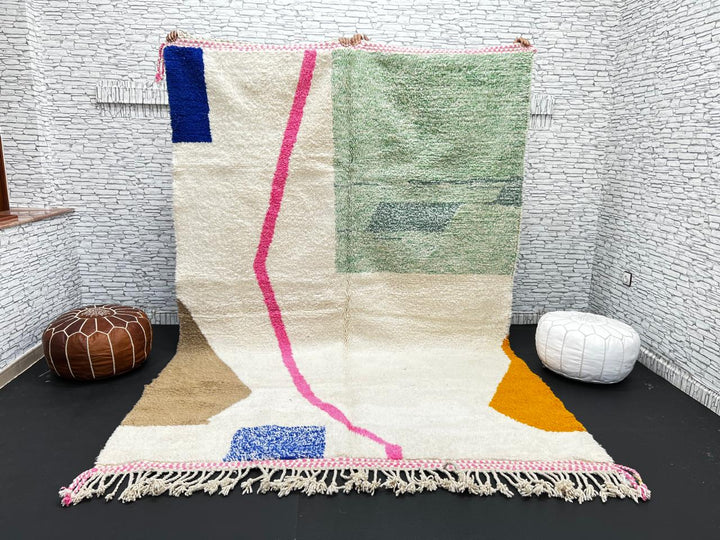 Modern Moroccan wool rug with abstract minimalist design featuring pink, green, and blue geometric accents, handmade by Berber artisans