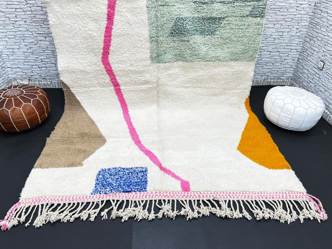 Modern Moroccan wool rug with abstract minimalist design featuring pink, green, and blue geometric accents, handmade by Berber artisans