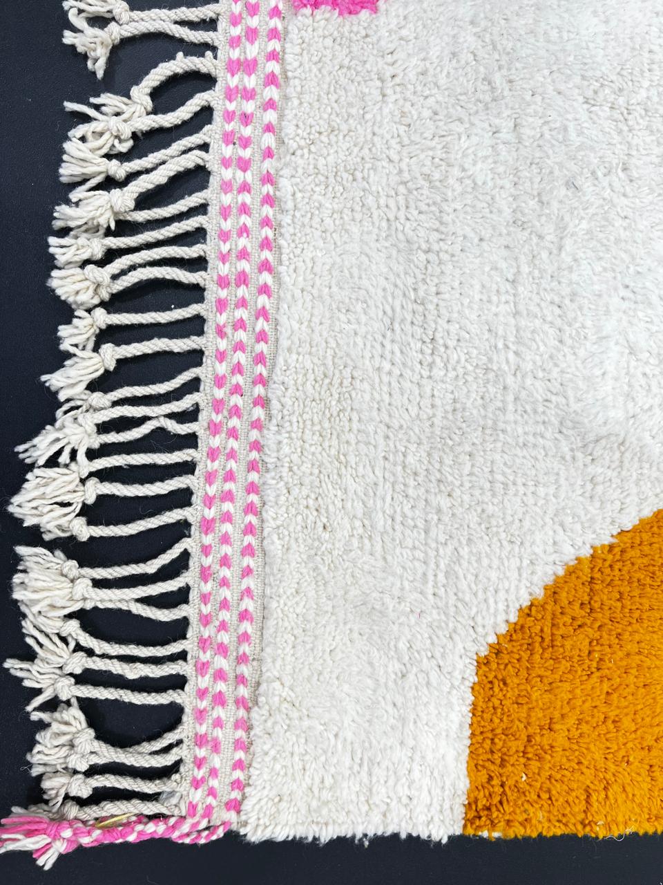 Modern Moroccan wool rug with abstract minimalist design featuring pink, green, and blue geometric accents, handmade by Berber artisans