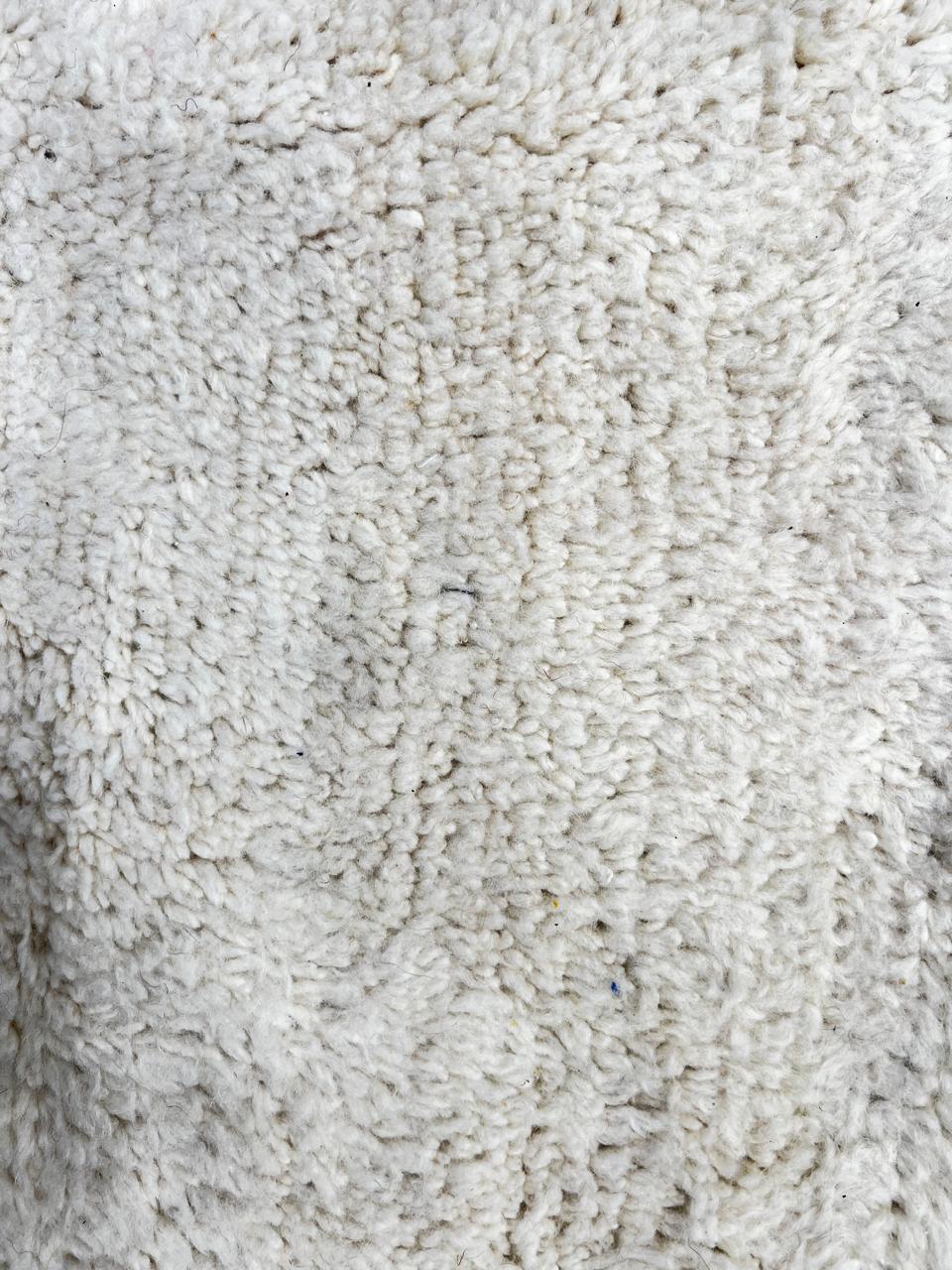 Modern Moroccan wool rug with abstract minimalist design featuring pink, green, and blue geometric accents, handmade by Berber artisans