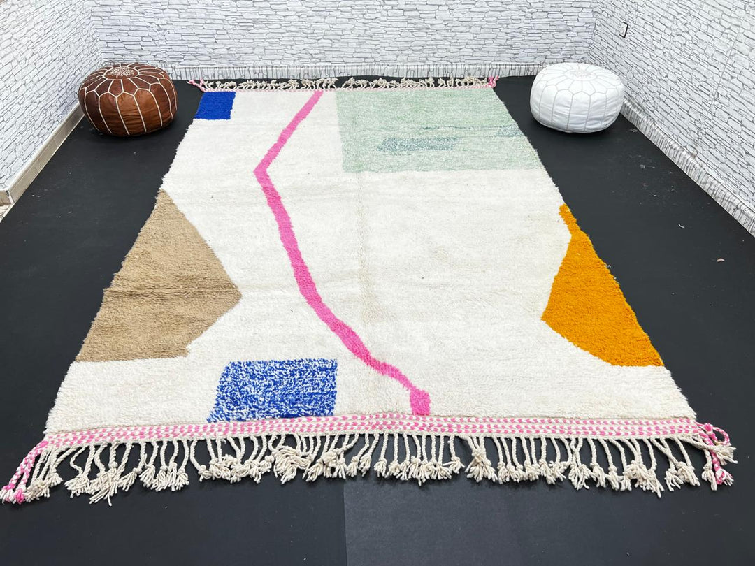 Modern Moroccan wool rug with abstract minimalist design featuring pink, green, and blue geometric accents, handmade by Berber artisans