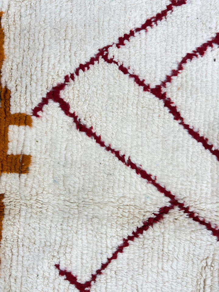 Modern Moroccan wool rug with abstract burgundy lines and golden geometric pattern on a white background