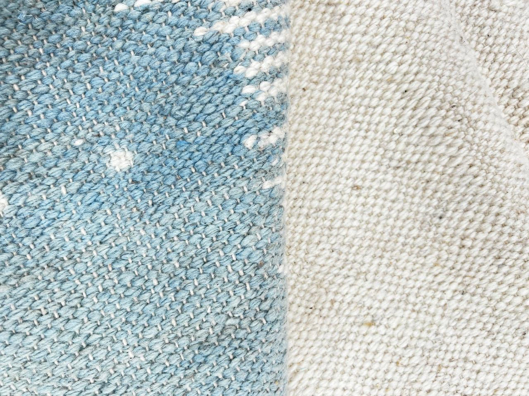 Flat weave round Moroccan wool rug with modern abstract design in terracotta, ivory, and soft blue tones
