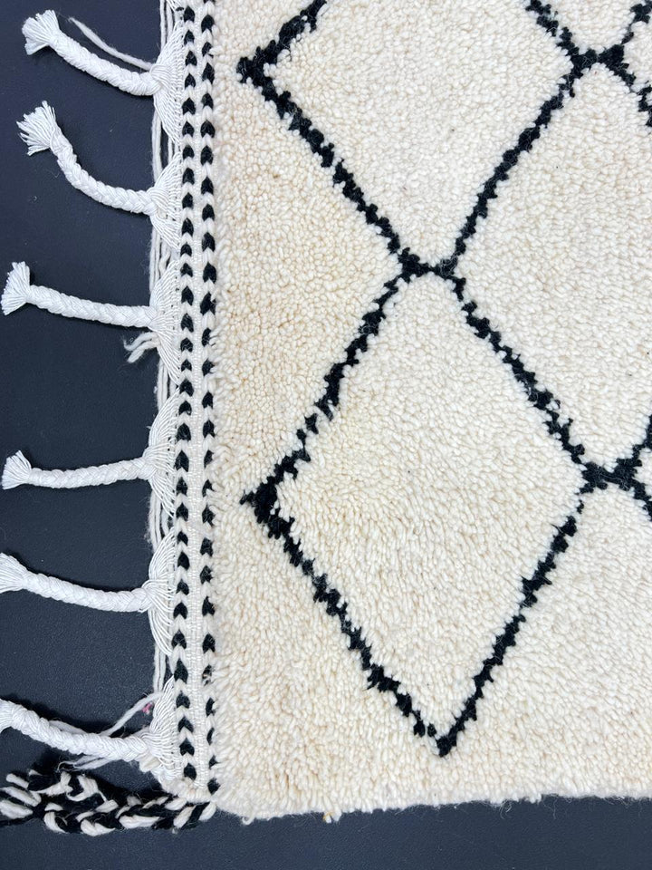 Handmade Moroccan runner rug with classic black diamond lattice design on a white wool background.