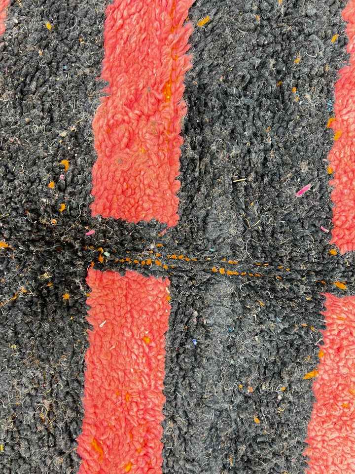 Orange Moroccan wool rug with bold geometric pattern in pink, black, blue, and yellow, handmade by Berber artisans