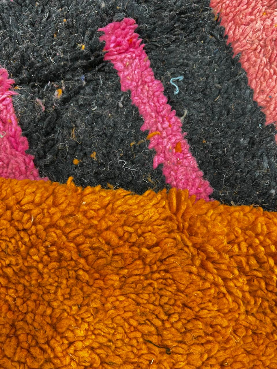 Orange Moroccan wool rug with bold geometric pattern in pink, black, blue, and yellow, handmade by Berber artisans