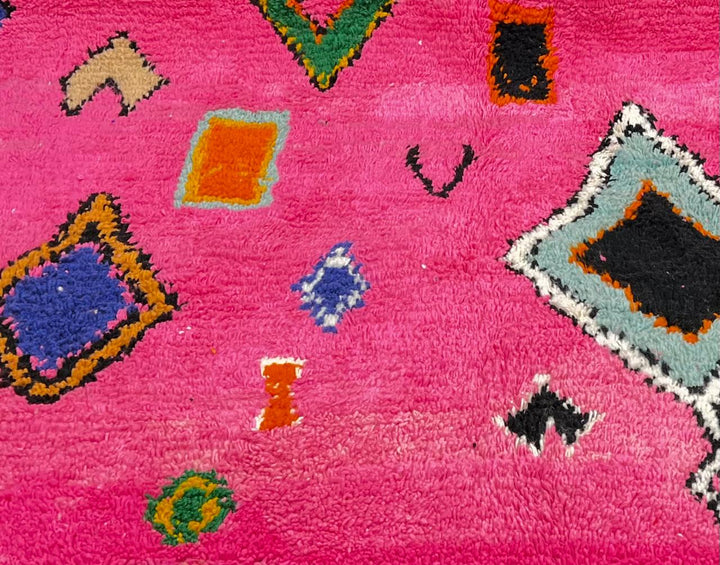 Handmade pink Moroccan runner rug with colorful geometric Berber motifs in green, blue, orange, yellow, and black.