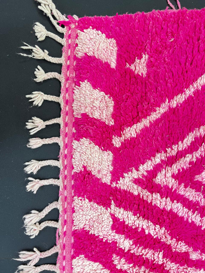 Pink Moroccan runner rug with geometric diamond pattern made of handmade wool and fringed edges on soft ivory background
