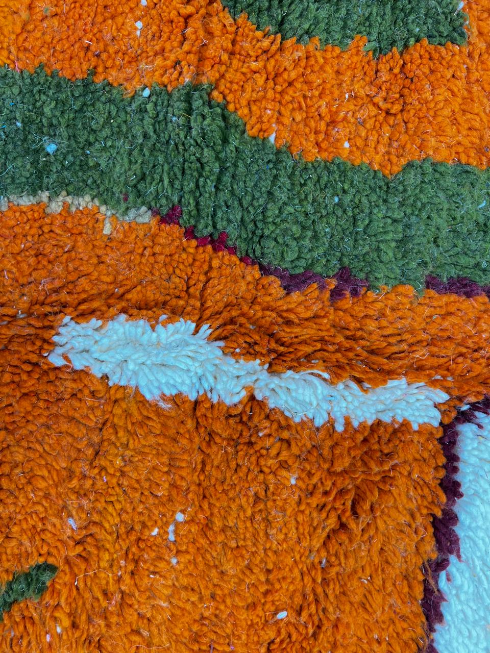 Round abstract Moroccan wool rug with blue, orange, green, and white modern design