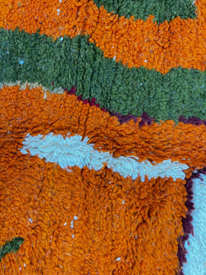 Round abstract Moroccan wool rug with blue, orange, green, and white modern design