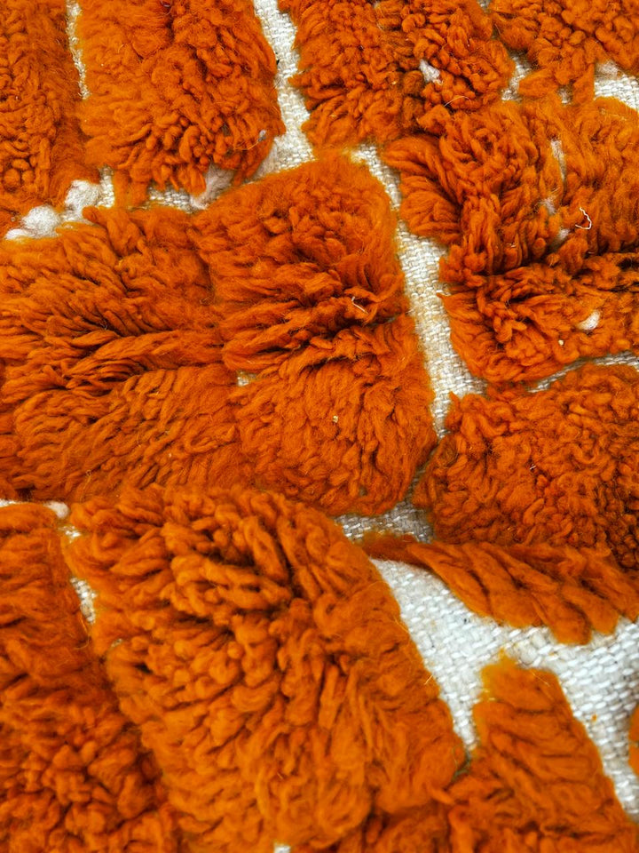 Round orange Moroccan wool shag rug with textured handwoven pattern on white background