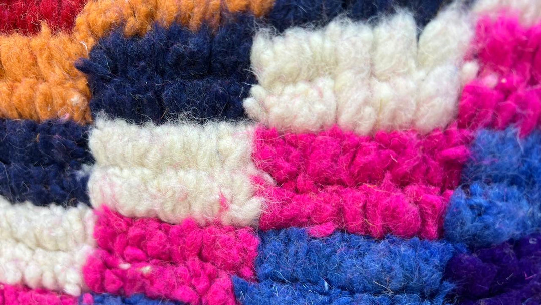 Round colorful Moroccan wool rug with abstract Berber pattern in pink, blue, green, yellow and ivory tones
