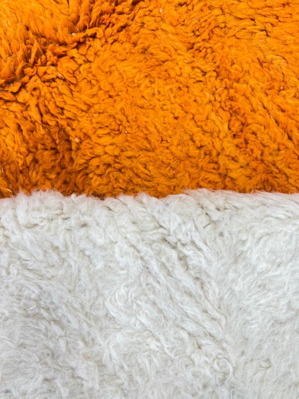 Round modern Moroccan rug with abstract orange, red, yellow, and white geometric design