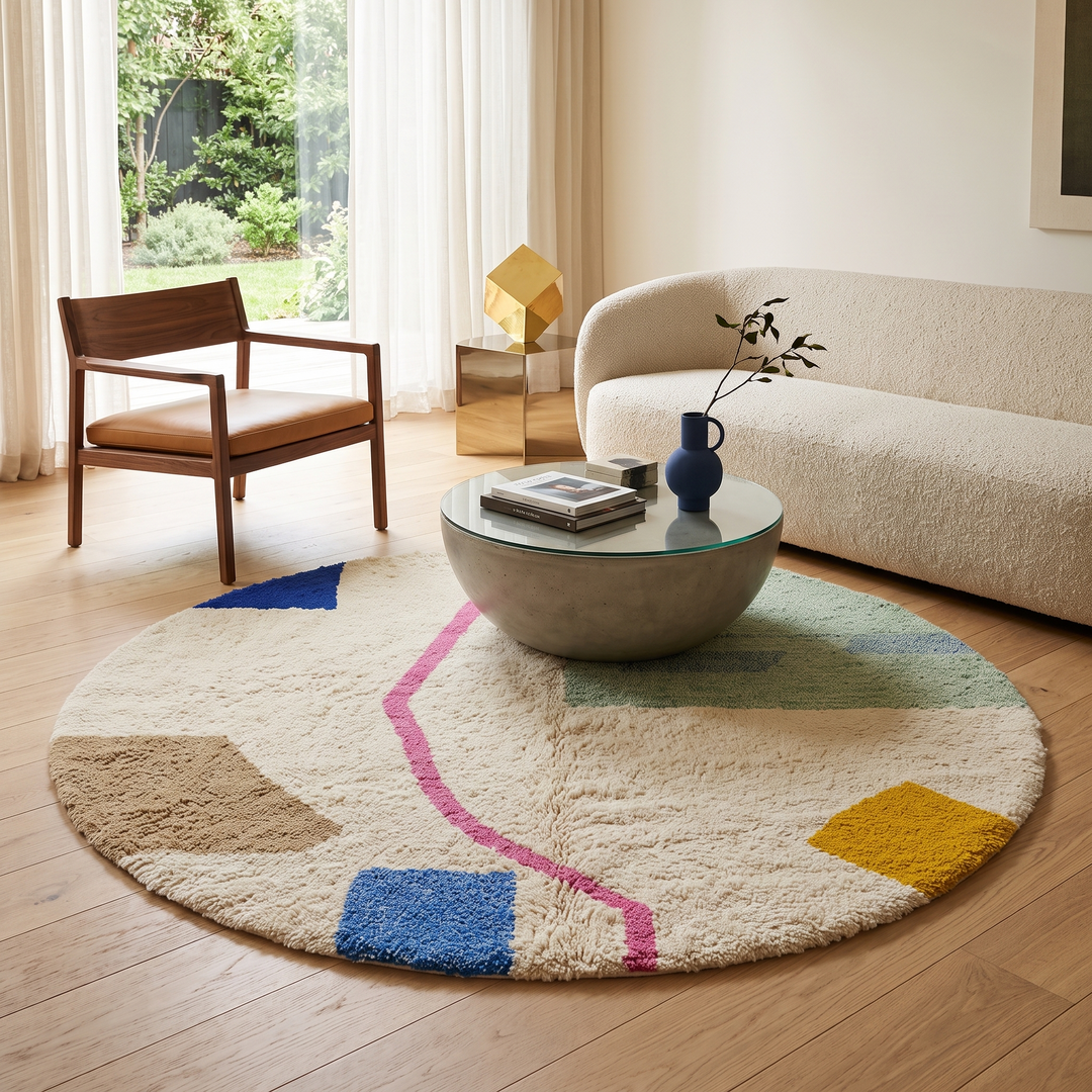 Round modern Moroccan wool rug with abstract pastel shapes and pink center line
