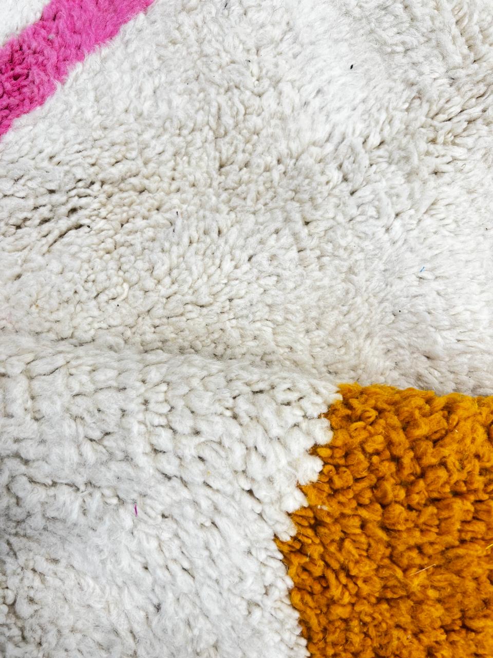 Round modern Moroccan wool rug with abstract pastel shapes and pink center line