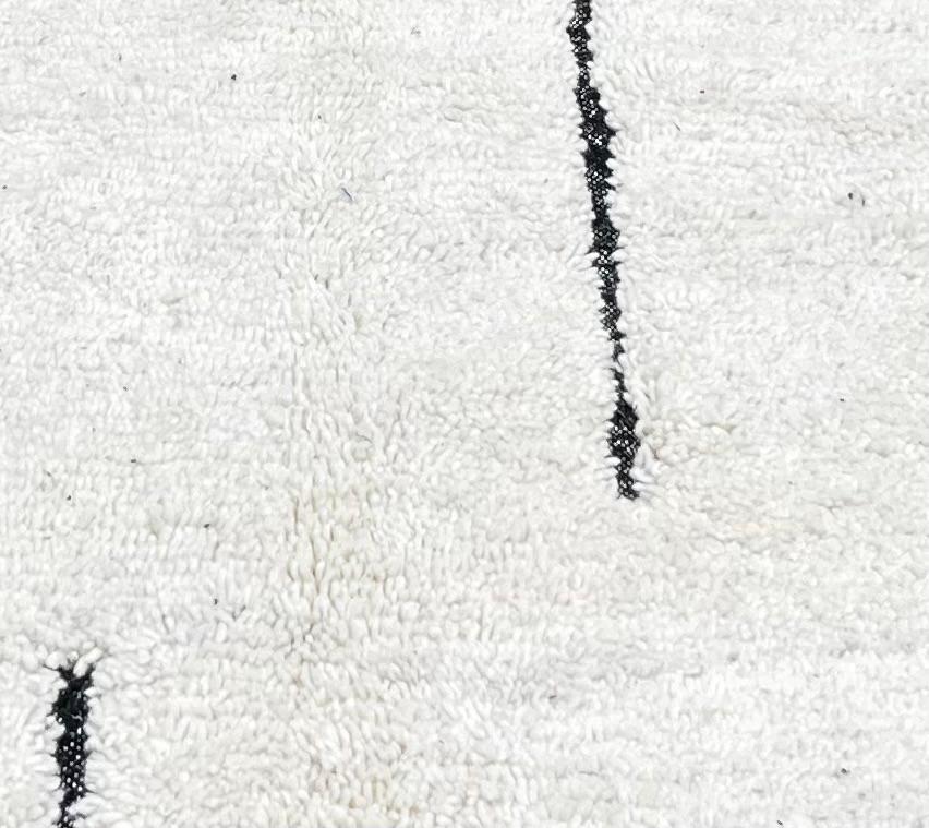 Round Moroccan rug with minimalist black abstract line pattern on a cream-white wool base