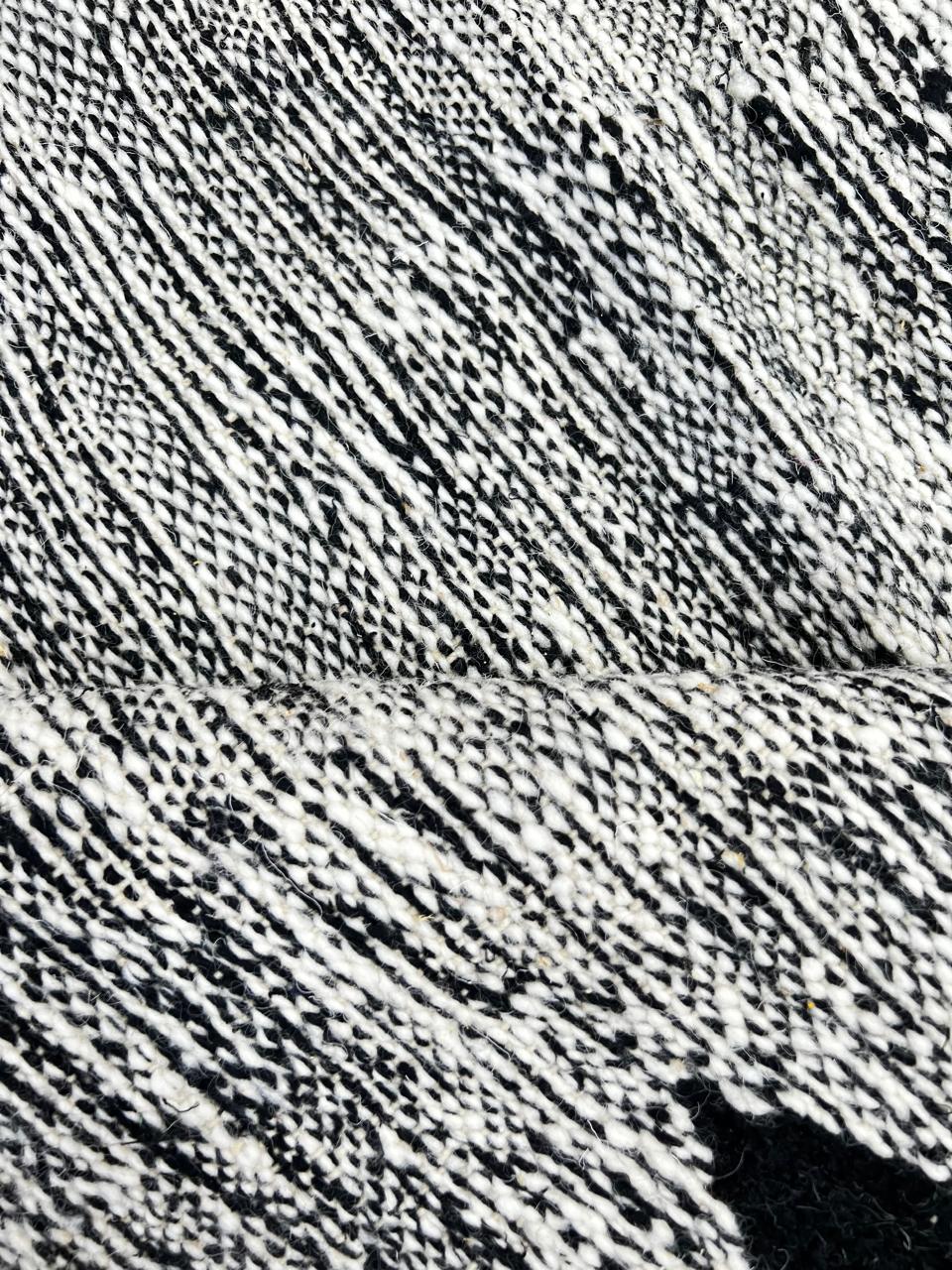 Handmade round Moroccan kilim rug with flatweave construction, featuring a black, and white zigzag geometric pattern.
