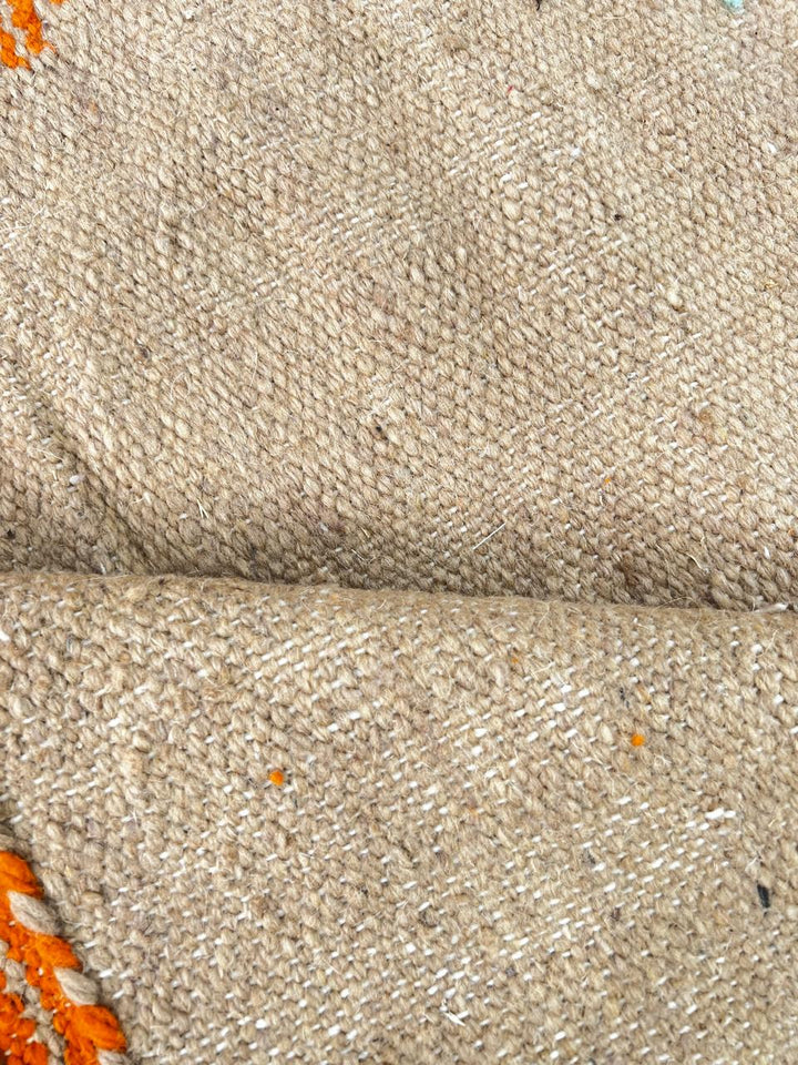 Handmade round Moroccan kilim rug with flatweave construction, featuring abstract earth tones in burnt orange, beige, and muted lavender.