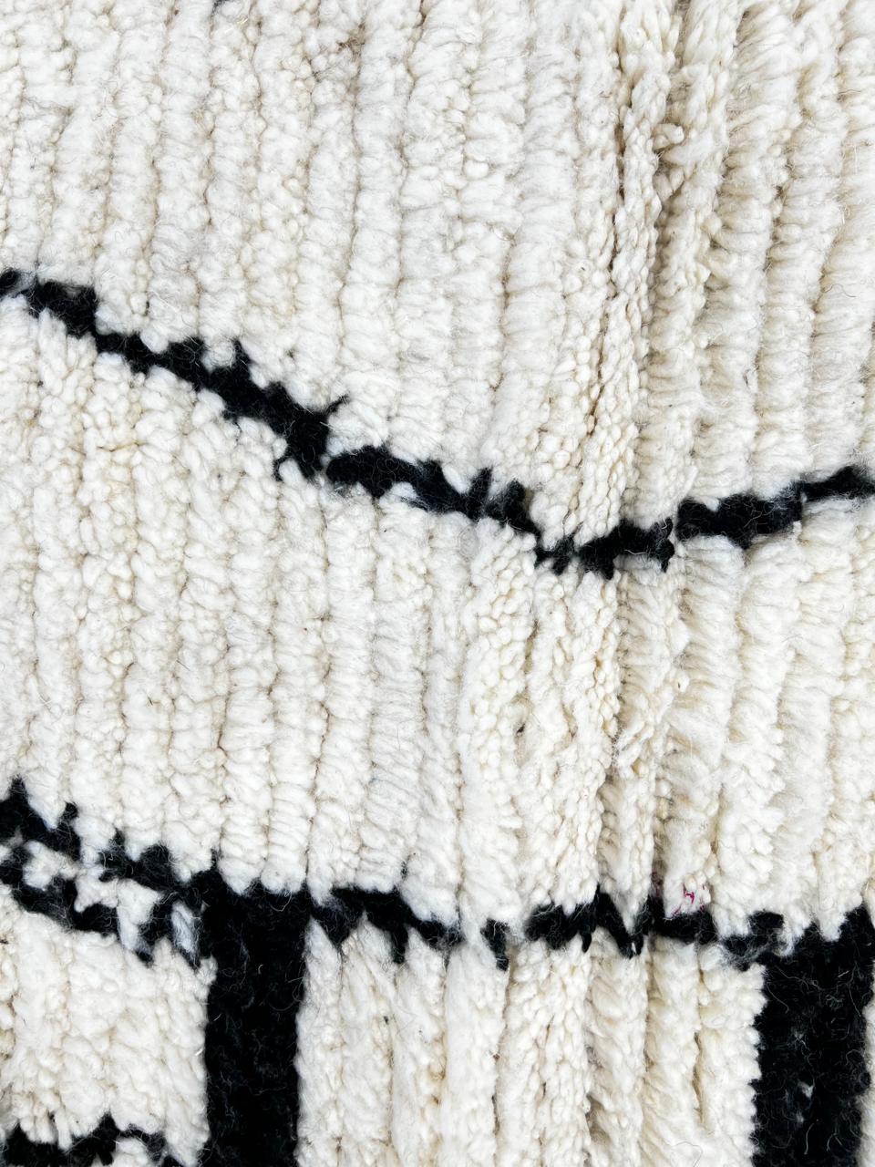 Handmade round Moroccan wool rug with traditional Berber symbols, featuring black geometric motifs on an white wool base.