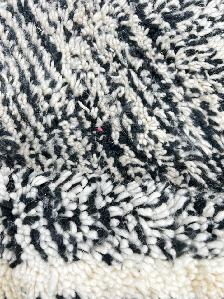 Round black and white Moroccan wool rug with geometric Berber diamond pattern on white background