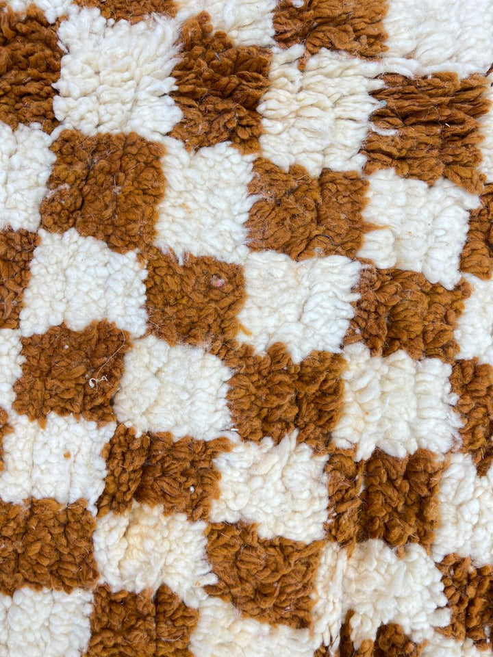 Handmade round brown and ivory Moroccan wool rug featuring a classic checkerboard geometric pattern.