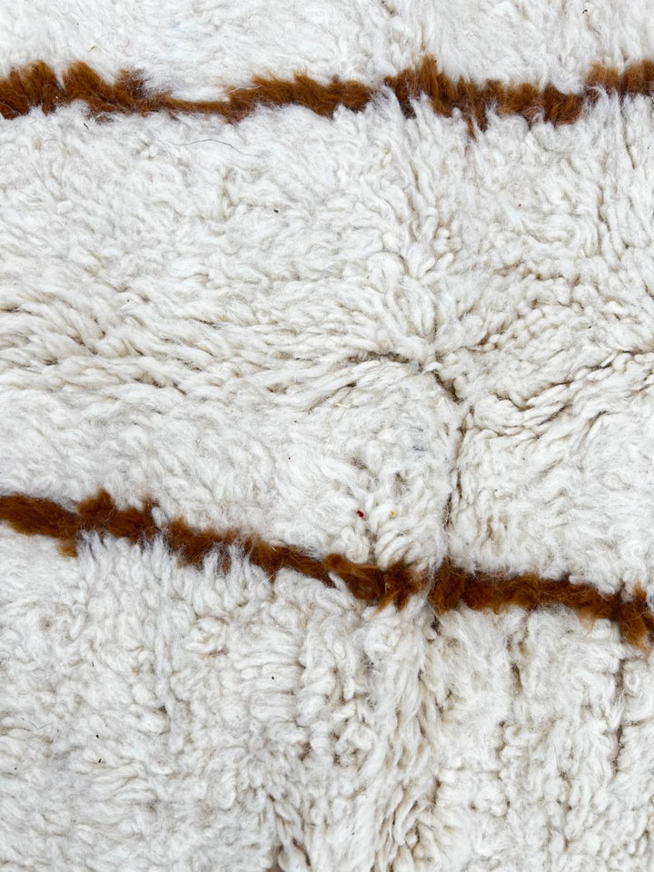 Round Moroccan wool rug with brown geometric lines on white.
