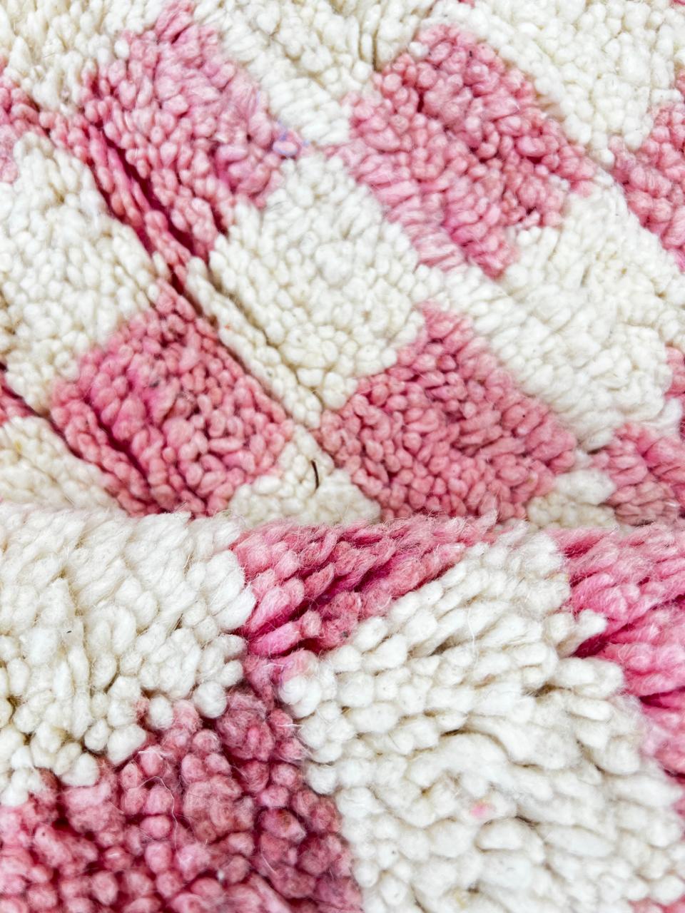 Handmade round Moroccan wool rug with pink and white checkerboard pattern, featuring a soft plush texture.