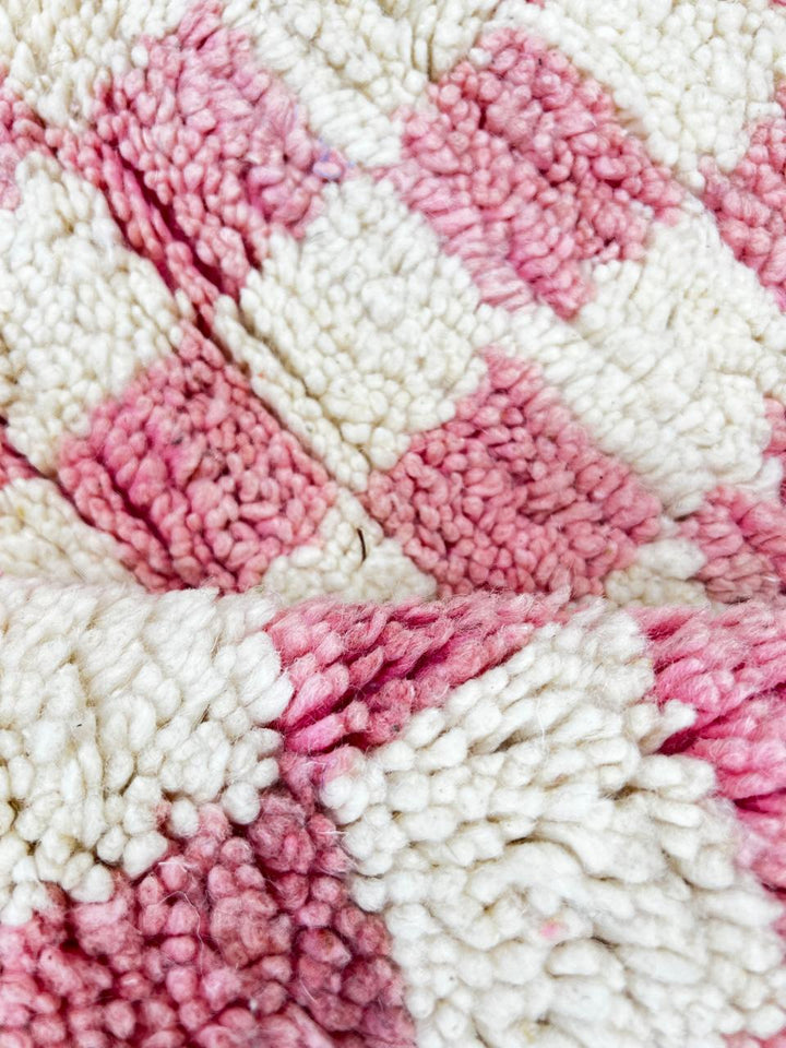 Handmade round Moroccan wool rug with pink and white checkerboard pattern, featuring a soft plush texture.
