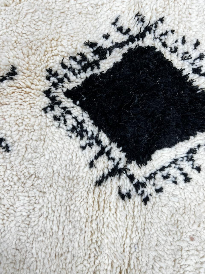 Round white Moroccan wool rug with black Berber symbols and geometric patterns on white background