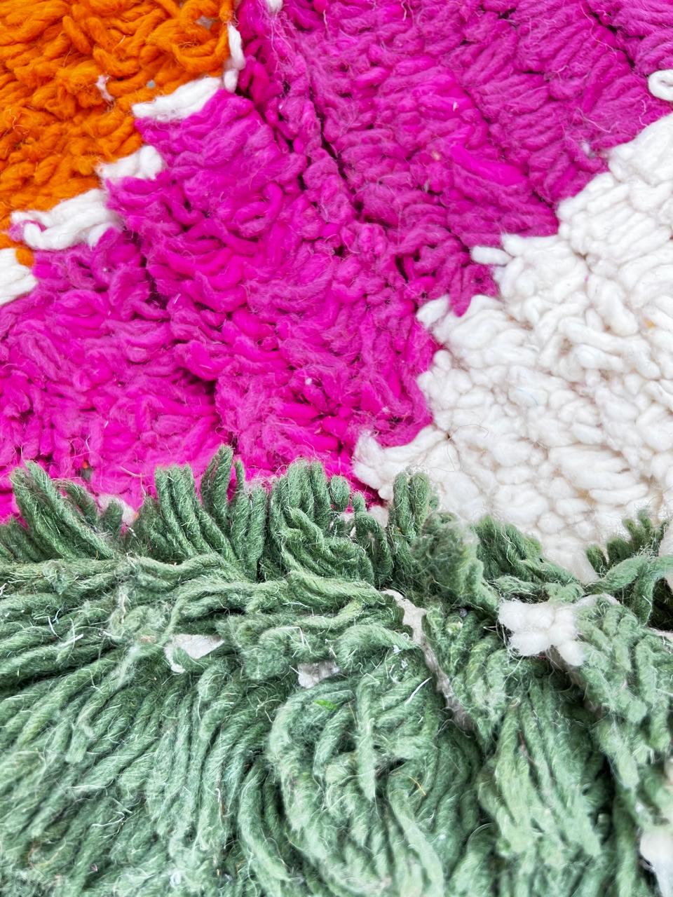 Colorful round Moroccan wool rug with abstract orange, pink, turquoise, mint green, and ivory geometric patterns.