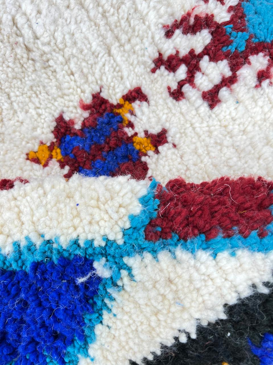 Handwoven Moroccan wool rug with colorful Berber tribal patterns and dark border