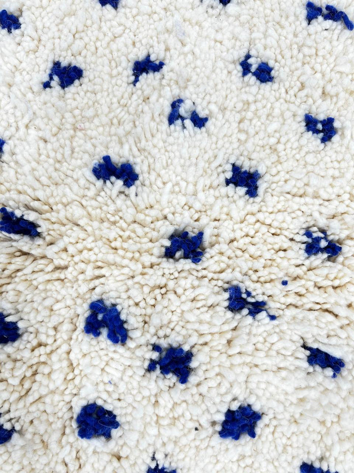 Handmade white Moroccan runner rug with small blue dotted pattern, woven from natural wool by Berber artisans.