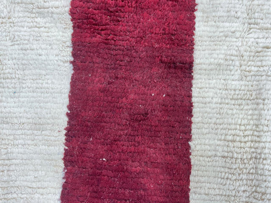 White Moroccan runner rug with a deep red vertical stripe and purple horizontal stripe, handmade from natural wool