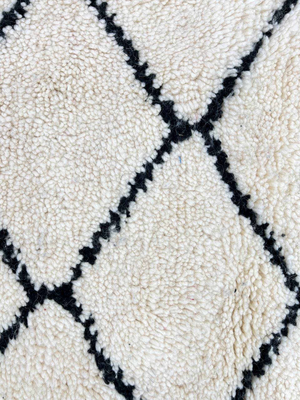 White round Moroccan wool rug with black diamond line pattern.