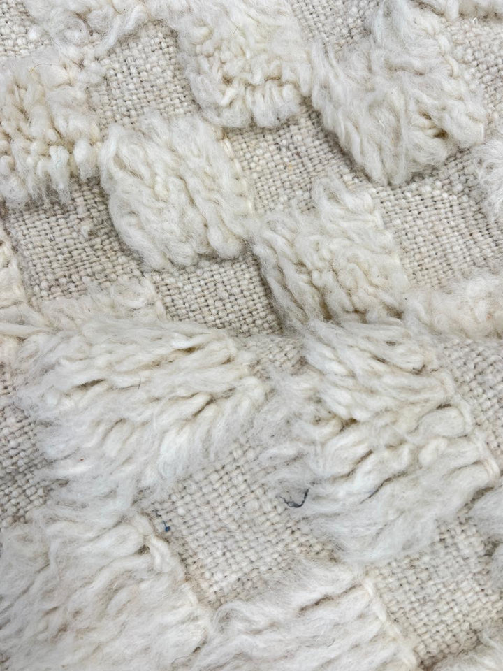Round white Moroccan wool rug with raised checkered 3D texture.
