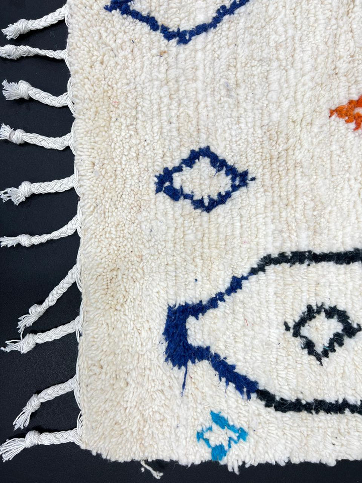 Handmade white Moroccan wool rug with blue, red, and orange geometric motifs – Berber design