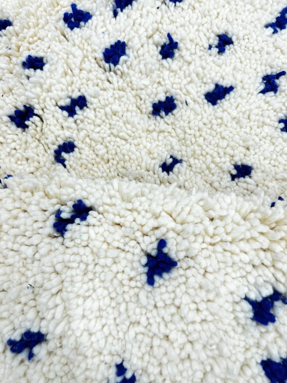 Round white Moroccan rug with small blue dotted pattern, handmade wool design